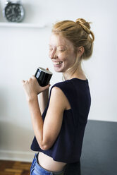 Young woman standing in kitchen, drinking coffee - VABF01343