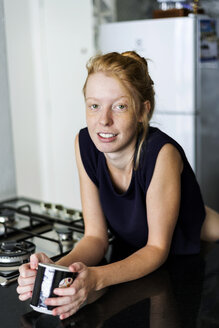Junge Frau steht in der Küche und trinkt Kaffee - VABF01344