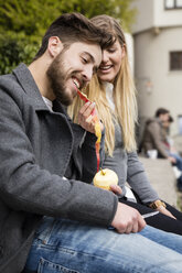 Junge Frau füttert ihren Freund mit der Schale eines Apfels - MIDF00824