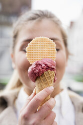 Woman's hand holding ice cream cone, close-up - MIDF00829