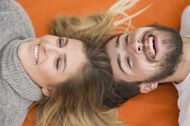 Portrarit eines lachenden Paares, das Kopf an Kopf auf einer Decke liegt - MIDF00836