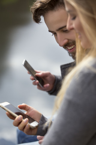 Junges Paar schaut auf ein Mobiltelefon, lizenzfreies Stockfoto
