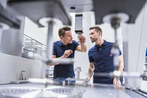 Two men at a machine in testing instrument room stock photo