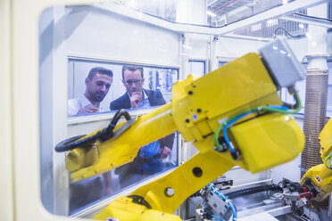 Zwei Männer in einer Fabrikhalle mit Blick auf eine Robotikmaschine - DIGF02181