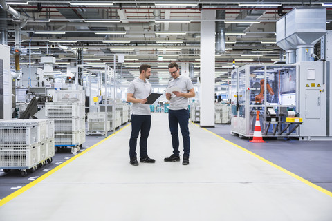 Two men talking in factory shop floor stock photo
