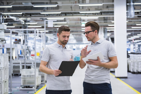 Zwei Männer unterhalten sich in einer Fabrikhalle - DIGF02190