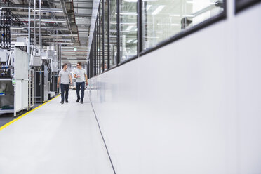 Two men walking and talking in factory shop floor - DIGF02205