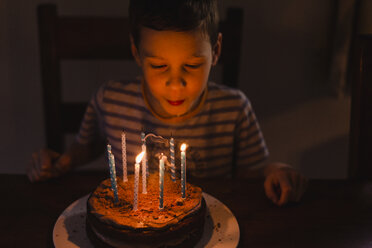 Junge bläst brennende Kerzen auf seinem Geburtstagskuchen aus - NMSF00057