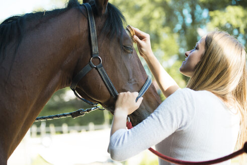 Young woman grooming horse - ZOCF00225