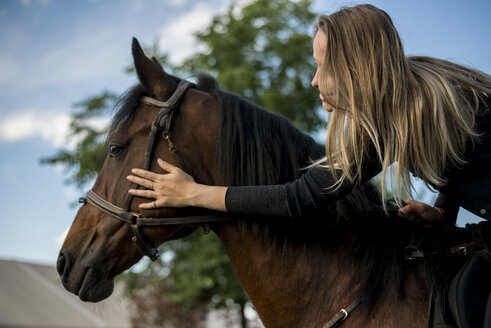 Young woman riding stroking horse - ZOCF00238