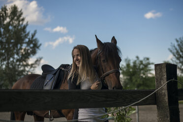 Lächelnde junge Frau mit Pferd auf einem Bauernhof - ZOCF00240