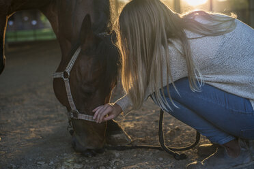 Young woman stroking horse - ZOCF00253