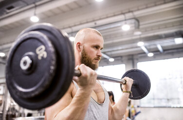 Junger Mann hebt Gewichte im Fitnessstudio - HAPF01562