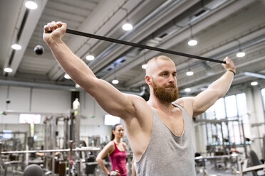 Junger Mann beim Training mit Fitnessband im Fitnessstudio - HAPF01565