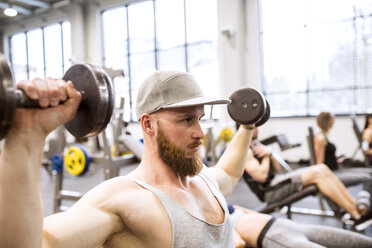 Junger Mann beim Training mit Hanteln im Fitnessstudio - HAPF01576