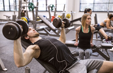 Junger Mann beim Training mit Hanteln im Fitnessstudio - HAPF01580