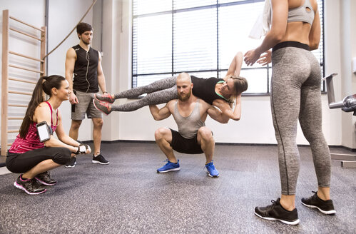 Junge Leute beim Fitnesstraining im Fitnessstudio, Heben von Partnern - HAPF01593