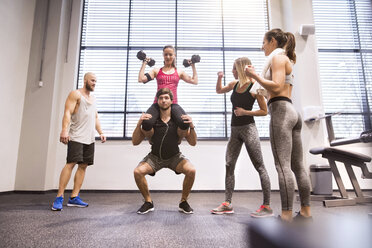 Junge Leute beim Fitnesstraining im Fitnessstudio, Heben von Partnern - HAPF01596