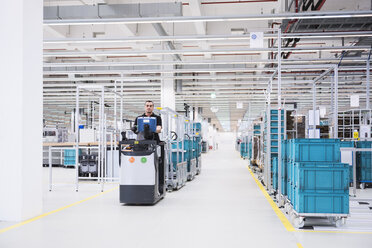 Man driving a tugger train in factory shop floor - DIGF02206