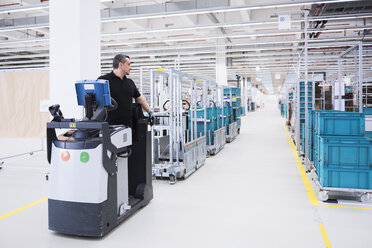 Man driving a tugger train in factory shop floor - DIGF02207