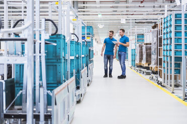 Two men with tablet talking in industrial hall at tugger train - DIGF02215