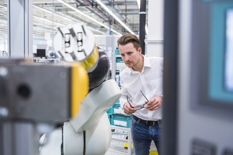 Man examining assembly robot in factory shop floor stock photo