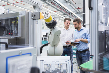 Two men with tablet examining assembly robot in factory shop floor - DIGF02254