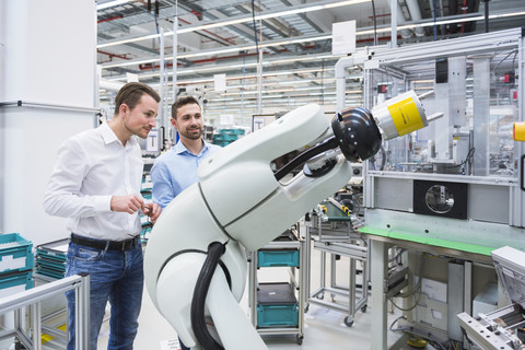Two men looking at assembly robot in factory shop floor stock photo