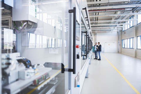 Two men with tablet talking in factory shop floor stock photo