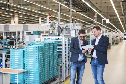 Two men with tablet talking in factory shop floor stock photo