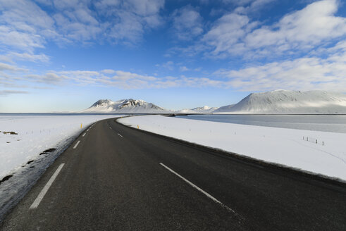 Empty road through Iceland with mountains in background - RAEF01868