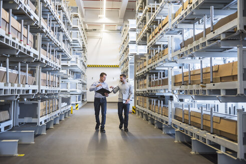 Two men walking in factory warehouse - DIGF02304