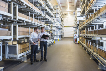 Two men talking in factory warehouse - DIGF02307