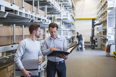 Two men talking in factory warehouse - DIGF02308