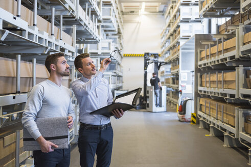 Zwei Männer unterhalten sich in einem Fabriklager - DIGF02309