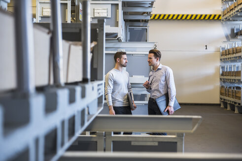 Two men talking in factory warehouse - DIGF02315