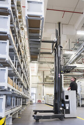 Worker operating forklift in factory warehouse - DIGF02316