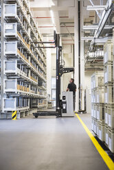 Worker operating forklift in factory warehouse - DIGF02317
