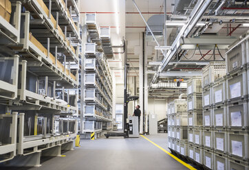 Worker operating forklift in factory warehouse - DIGF02318