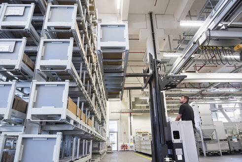 Worker operating forklift in factory warehouse - DIGF02319