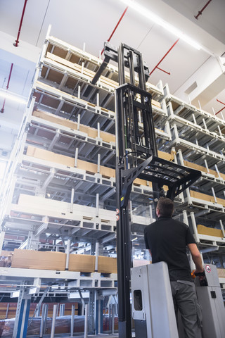 Worker operating forklift in factory warehouse stock photo