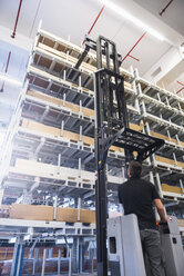 Worker operating forklift in factory warehouse - DIGF02320