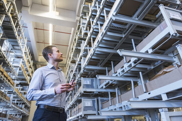 Man in factory warehouse looking at shelves - DIGF02323