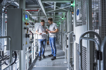 Two men in automatized high rack warehouse looking at tablet - DIGF02328