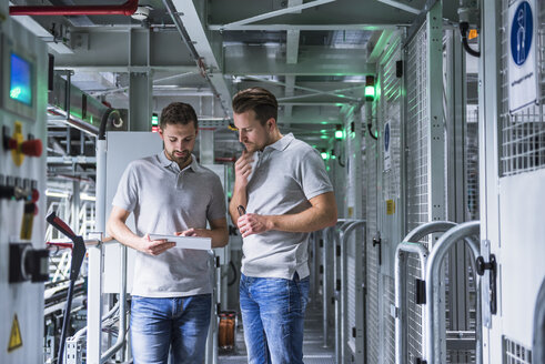 Two men in automatized high rack warehouse looking at tablet - DIGF02329