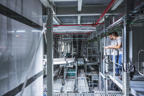 Two men talking in automatized high rack warehouse - DIGF02330