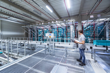 Man with documents in automatized high rack warehouse - DIGF02335