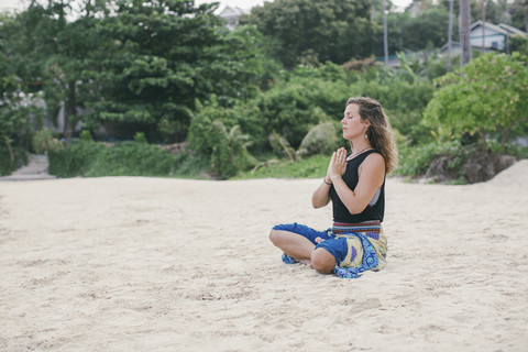 Frau übt Yoga am Strand, lizenzfreies Stockfoto