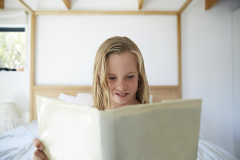 Porträt eines zufriedenen kleinen Mädchens, das zu Hause ein Buch liest, lizenzfreies Stockfoto