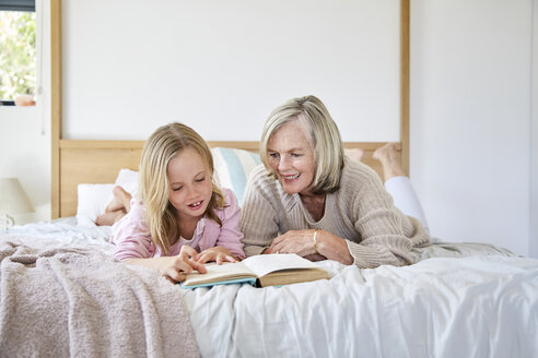 Kleines Mädchen liegt mit ihrer Großmutter auf dem Bett und liest ein Buch - SRYF00270